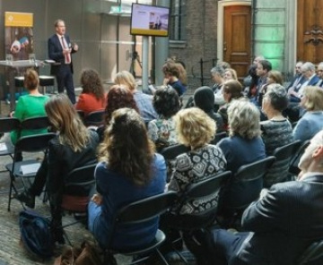 mensen zitten in een zaal naar een man te luisteren