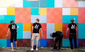 kleurrijke muur wordt getoond met enkele heren ervoor