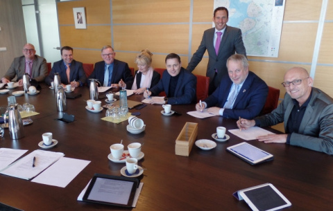 groep mensen poseert aan een vergadertafel