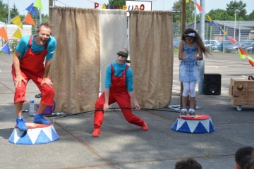 een circusartiest doet truukjes met twee kinderen