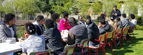 groep mensen zitten aan tafel en luisteren naar een man