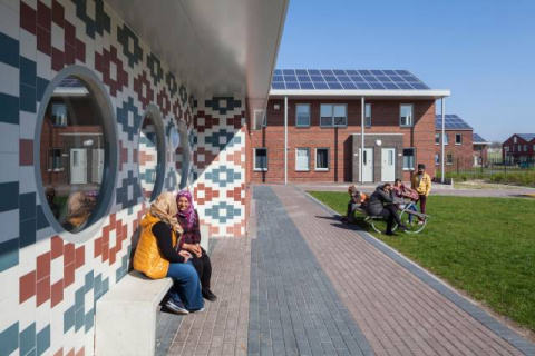 bewoners van azc voor het pand met zonnepanelen