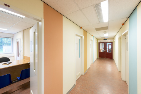 Gang met blauwe, gele en oranje verticale strepen op de muur en deuren aan weerszijden