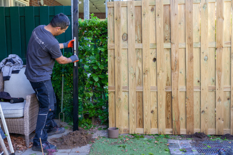 Man klust in iemands tuin, staat voor schutting