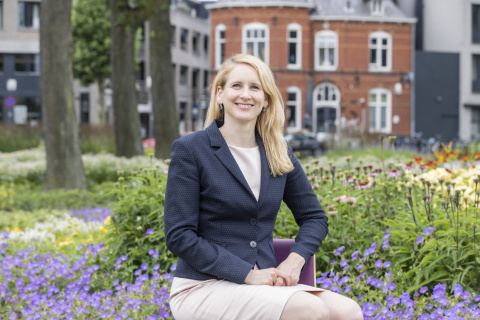 vrouw zit op bankje in park, paarse bloemen om haar heen