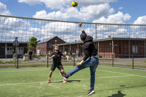 sporters buiten in actie bij volleybal net
