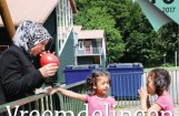 twee meisjes staan bij een vrouw die een ballon opblaast