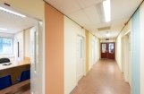 Gang met blauwe, gele en oranje verticale strepen op de muur en deuren aan weerszijden