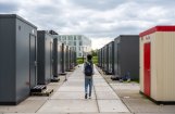 Bewoner met rugzak loopt tussen de woonunits van noodopvanglocatie