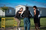 drie mannen met een voetbal en huizen op de achtergrond