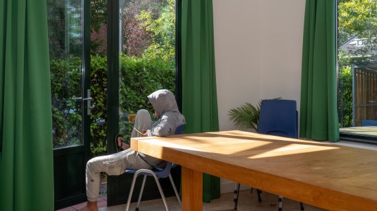 Jongen met capuchon op kijkt naar buiten