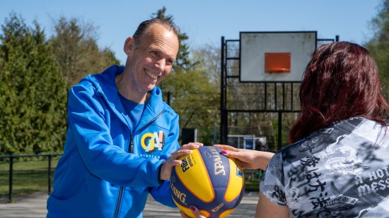 trainer geeft bal aan bewoner